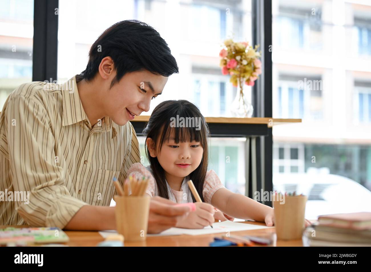Alegre maestro de arte masculino asiático está enseñando y mostrando cómo dibujar animales lindos a su joven estudiante femenina. Niños con Arte Concepto Foto de stock