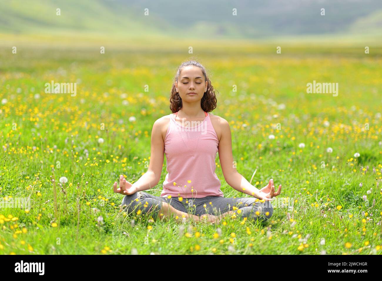 Vista frontal retrato de un yogui haciendo yoga en la hierba de la montaña Foto de stock