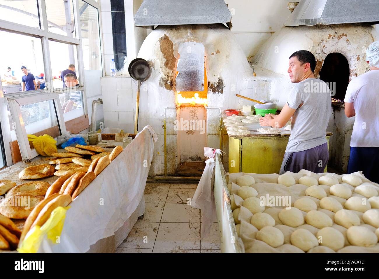 Tashkent Uzbekistan - Panaderos que elaboran pan local redondo fresco en una panadería en el mercado del Bazar de Chorsu en agosto de 2022 Foto de stock