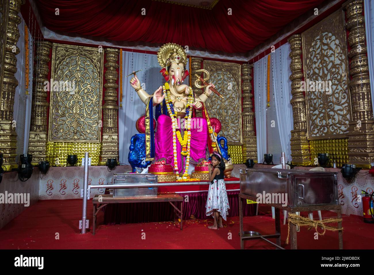 Una niña pequeña ante un hermoso ídolo del Señor Ganesha en un mandal en Mumbai para el auspicioso festival indio de Ganesh Utsav Foto de stock