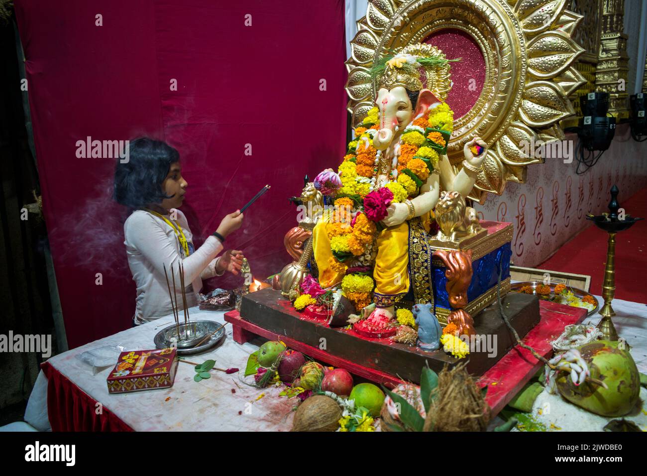 Una niña pequeña ante un hermoso ídolo del Señor Ganesha en un mandal en Mumbai para el auspicioso festival indio de Ganesh Utsav Foto de stock