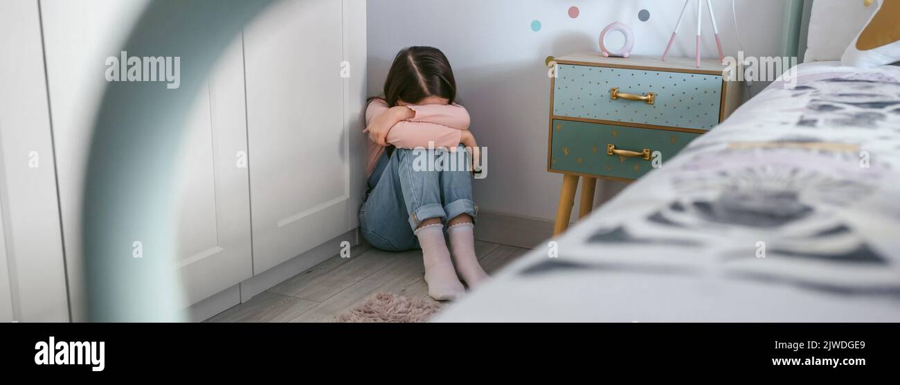 Una chica irreconocible llorando en el suelo de su dormitorio Foto de stock