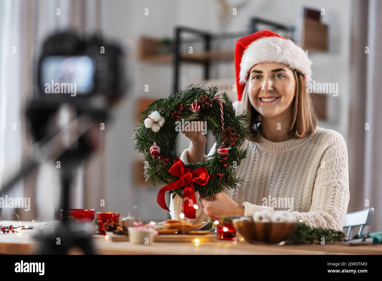 mujer con cámara y corona de navidad de abeto en casa Foto de stock