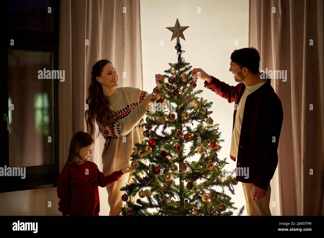 Familia feliz decorar árbol de navidad en casa Foto de stock