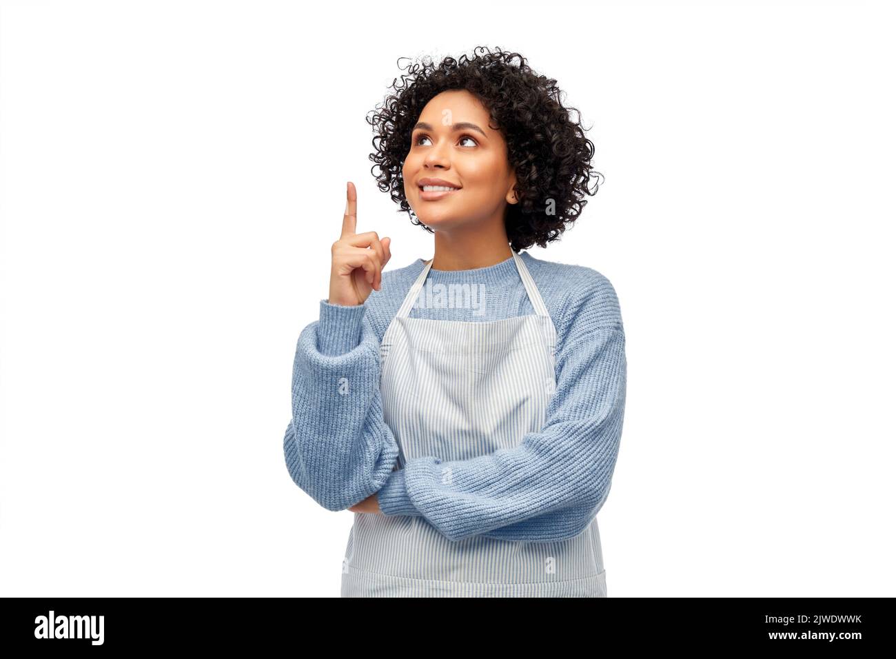 mujer sonriente en el delantal señalando con el dedo hacia arriba Foto de stock