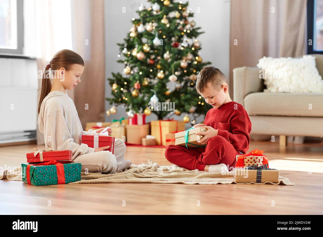 niños felices abriendo regalos de navidad en casa Foto de stock
