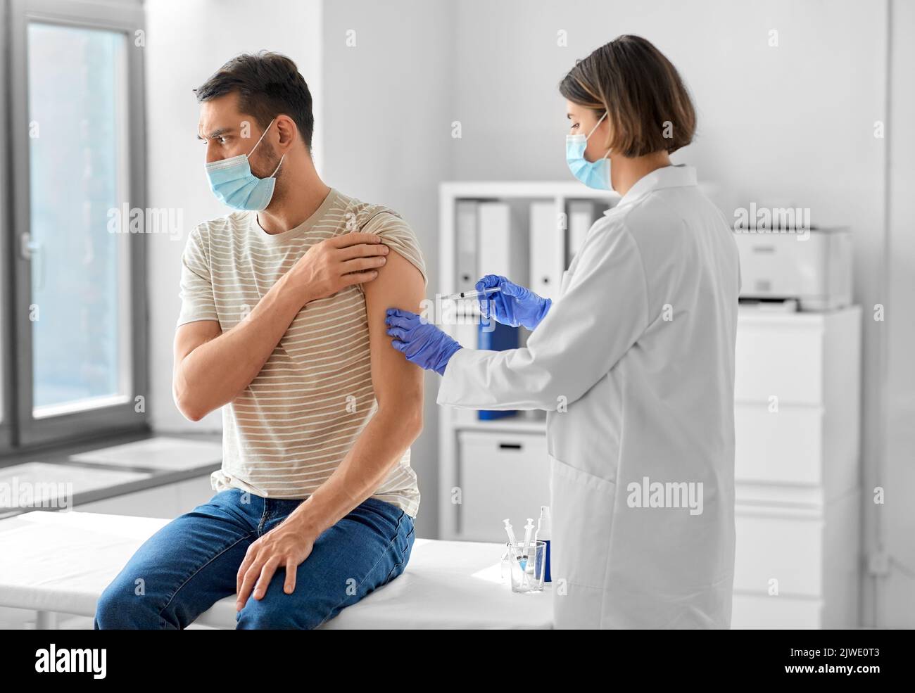 médico con jeringa vacunando paciente masculino Foto de stock