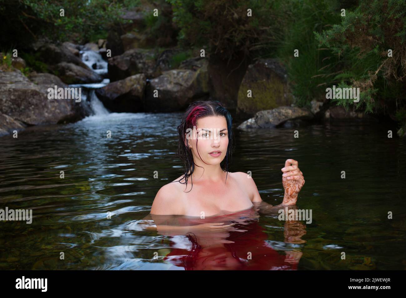 Una hermosa mujer enfriándose en un arroyo de montaña Foto de stock