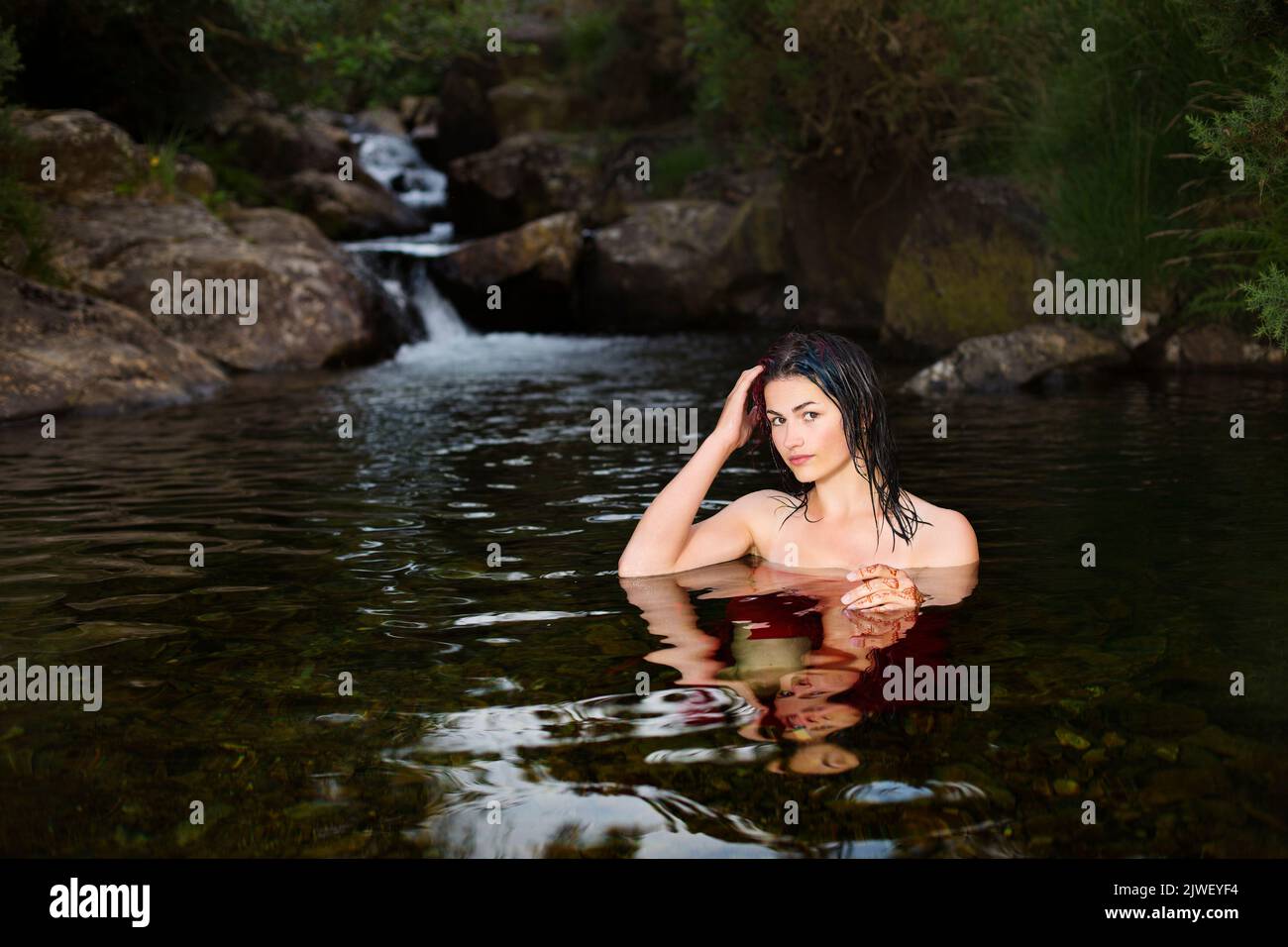 Una hermosa mujer enfriándose en un río Foto de stock