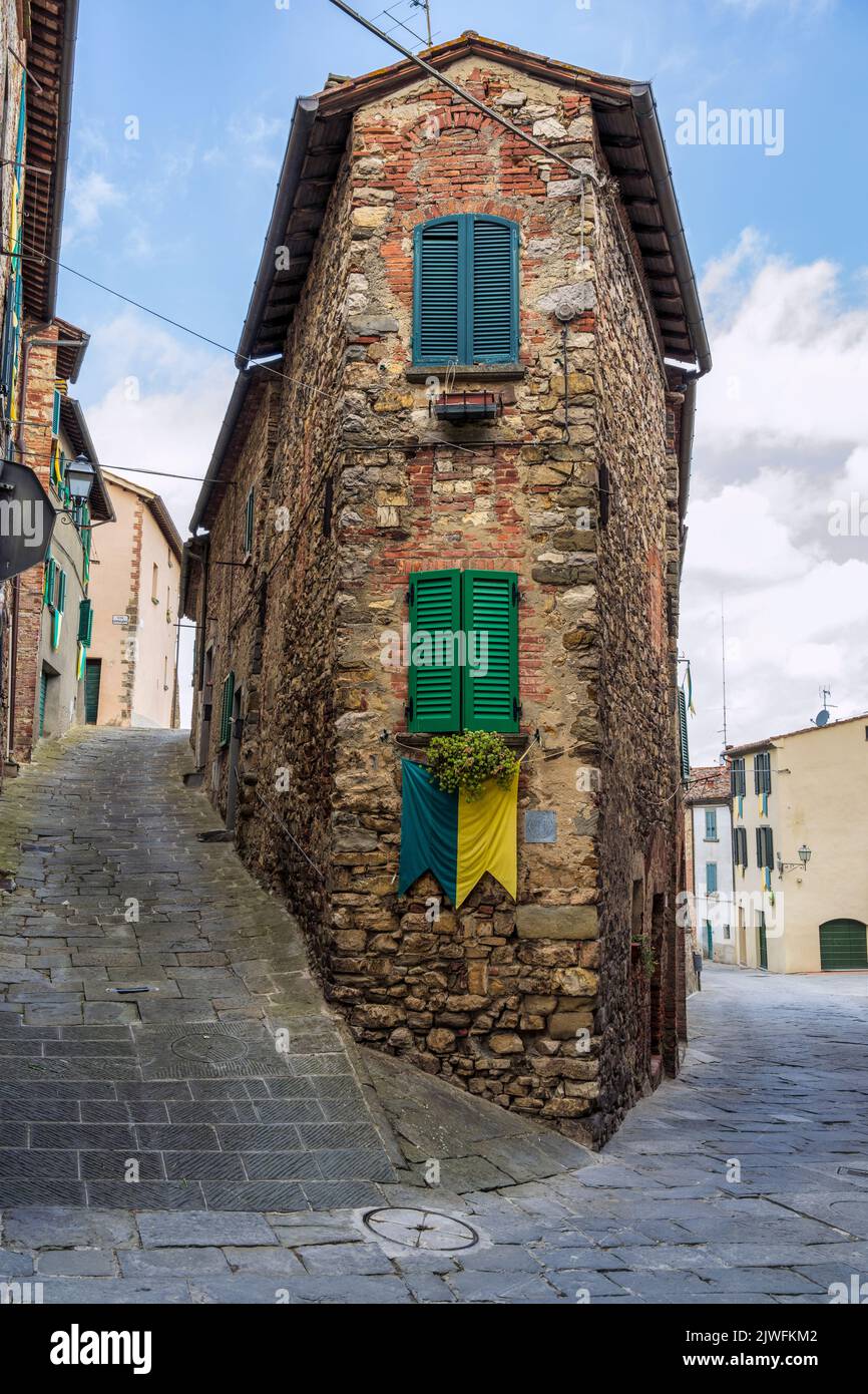Edificio medieval en la esquina de Via Roma en la ciudad medieval de Lucignano en la cima de la colina en el Val di Chiana en Toscana, Italia Foto de stock