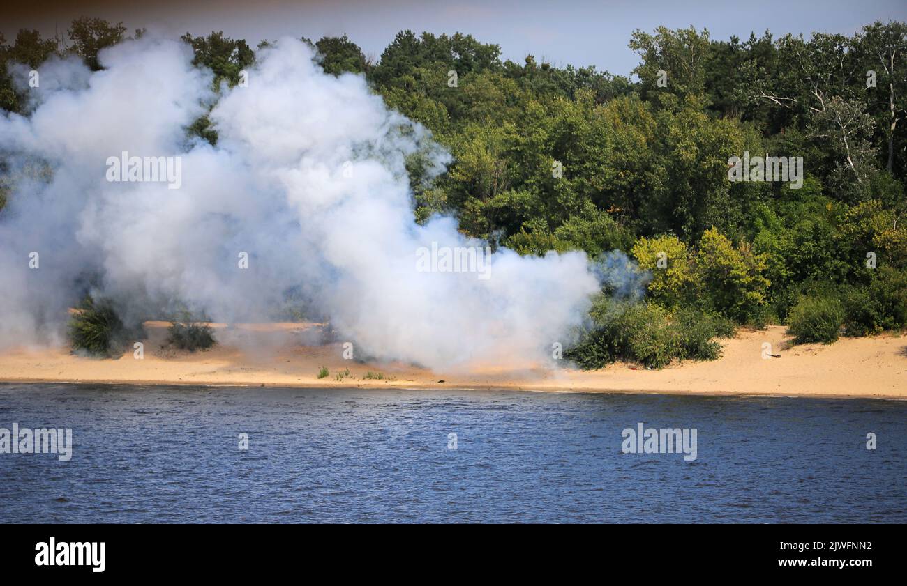 Humo y fuego salvaje en la orilla del río Foto de stock