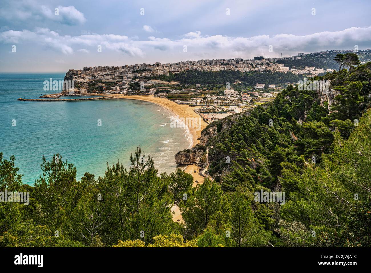 Paisaje de la bahía con la playa de arena y la ciudad turística de Peschici encaramado en los acantilados con vistas al mar Adriático. Peschici, Apulia Foto de stock