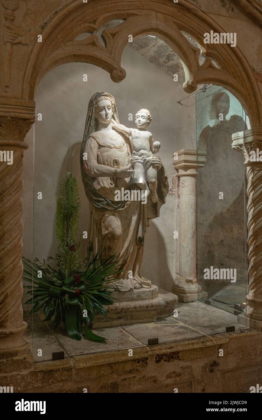 La estatua de la Virgen María con el niño en sus brazos a lo largo de la escalera interior que conduce a la cueva de San Michele. Monte Sant' Angelo, Puglia Foto de stock