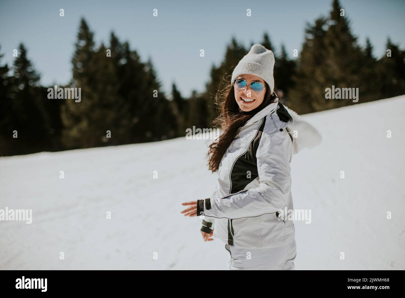 Mujer joven parada en la pista de esquí en un día soleado Foto de stock