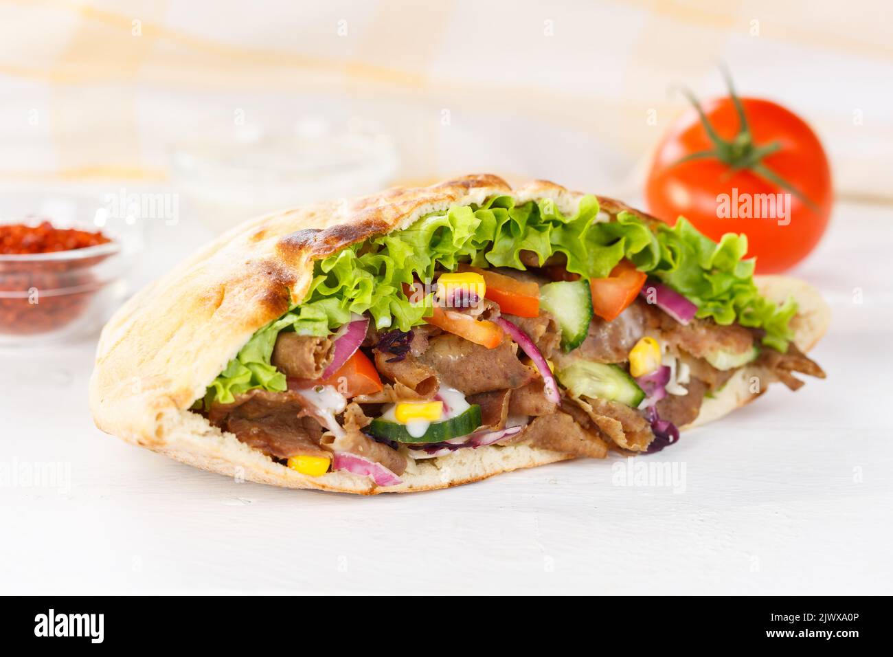Döner Kebab Doner Kebap comida rápida en pan plano en un bocadillo de madera Foto de stock