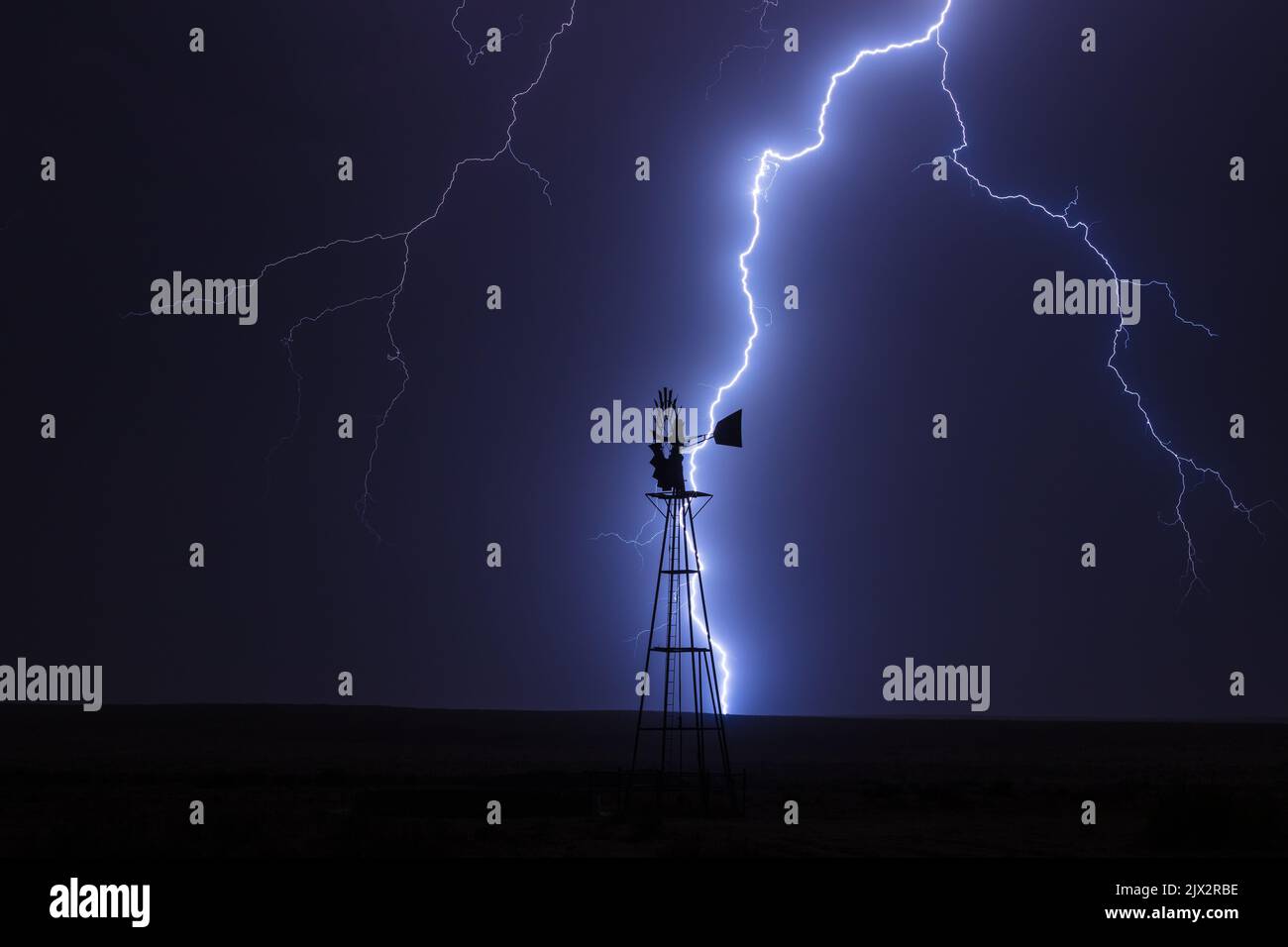 Un rayo golpea detrás de un molino de viento durante una tormenta cerca de Campo, Colorado Foto de stock