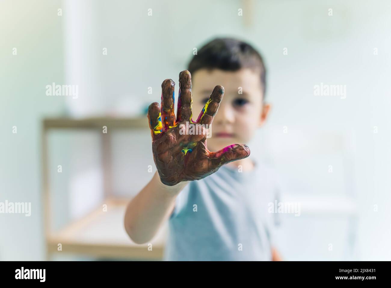 Pintura de película adhesiva. Niños pequeños pintando con una esponja, pinceles y pinturas sobre una película adhesiva envuelta todo el camino alrededor de la unidad de estante de madera. Un maestro que les ayuda. Actividad creativa para niños Desarrollo de habilidades sensoriales en la guardería. Fotografía de alta calidad Foto de stock