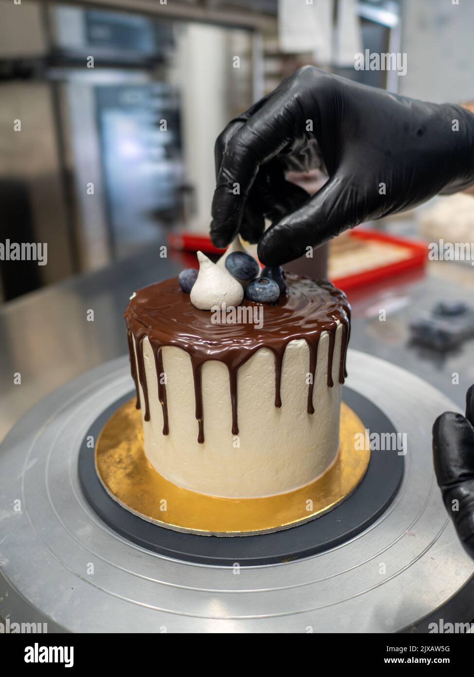 trabajador irreconocible preparando una torta de chocolate y bayas que gotean dulces Foto de stock
