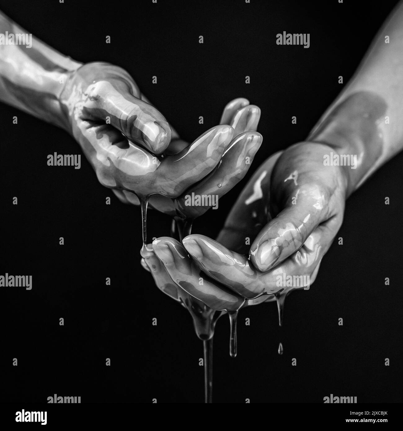 Las manos de las mujeres en un líquido viscoso similar a la sangre. Foto en blanco y negro. Foto de stock