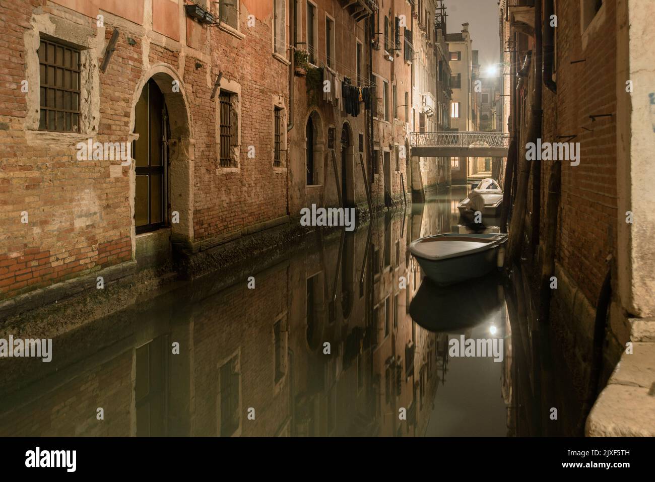 Noche veneciana tranquila con barcos estacionados y luces reflejo en el canal de la ciudad Foto de stock