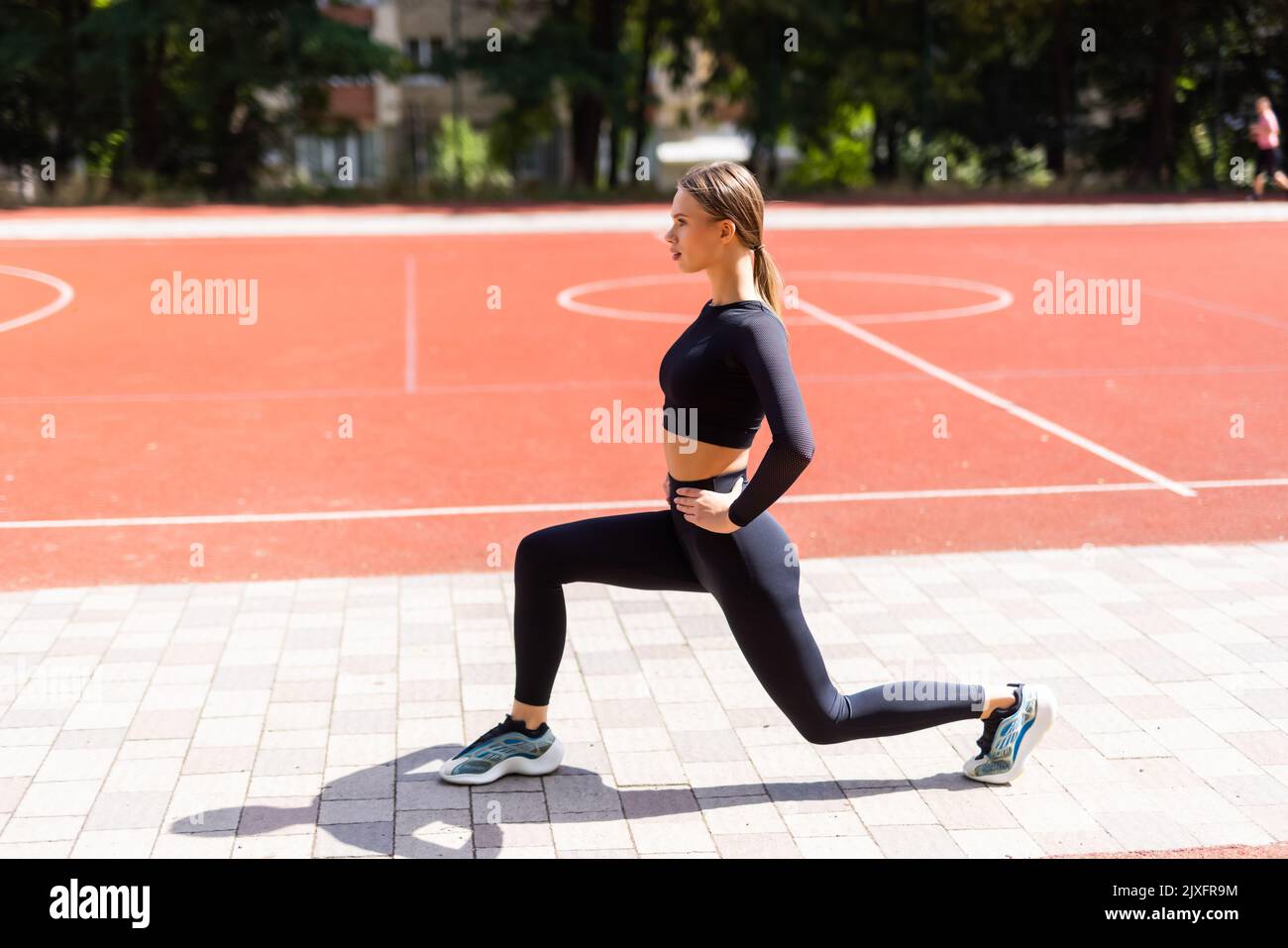 La dama atlética está teniendo entrenamiento haciendo sentadas mientras que pone las manos en la cintura. Foto de stock