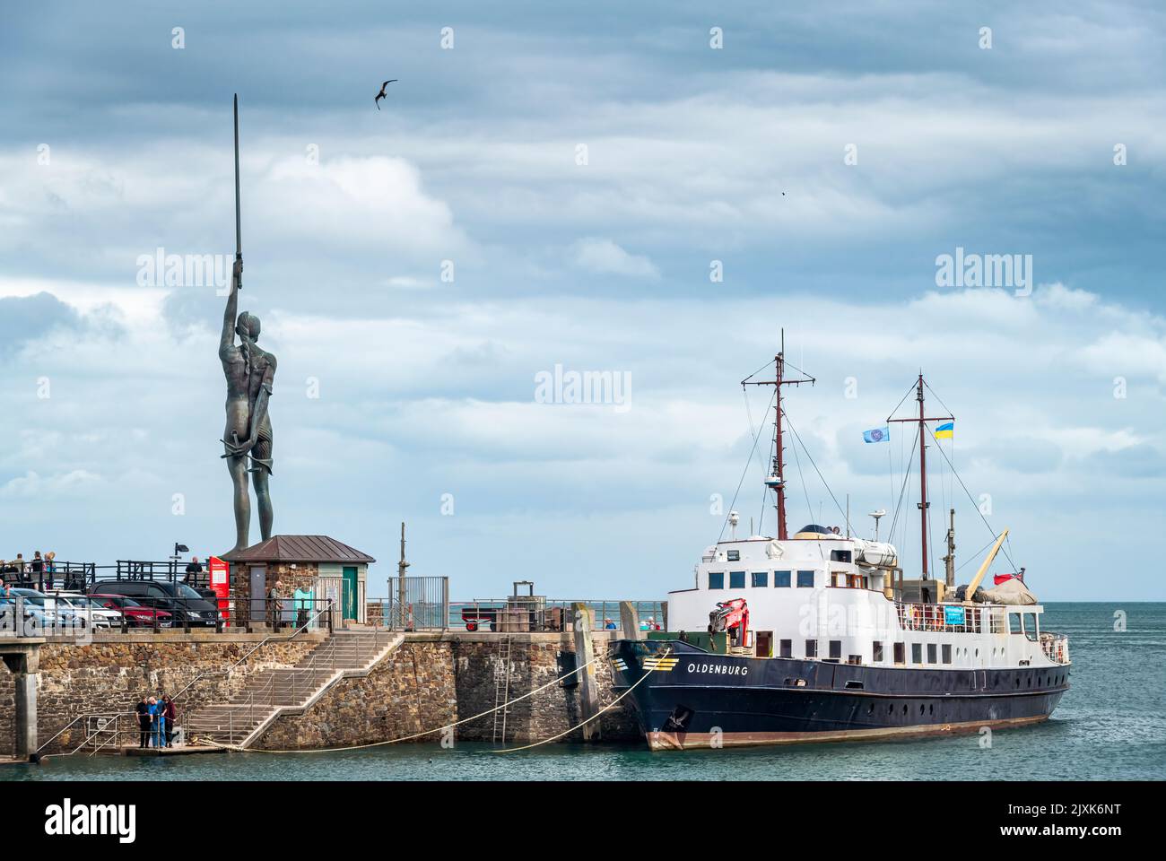 El barco de suministro de la isla Lundy y el barco de pasajeros MV Oldenburg amarrado junto al muelle, con la famosa estatua de Damien Hirst Verity en el fondo Foto de stock