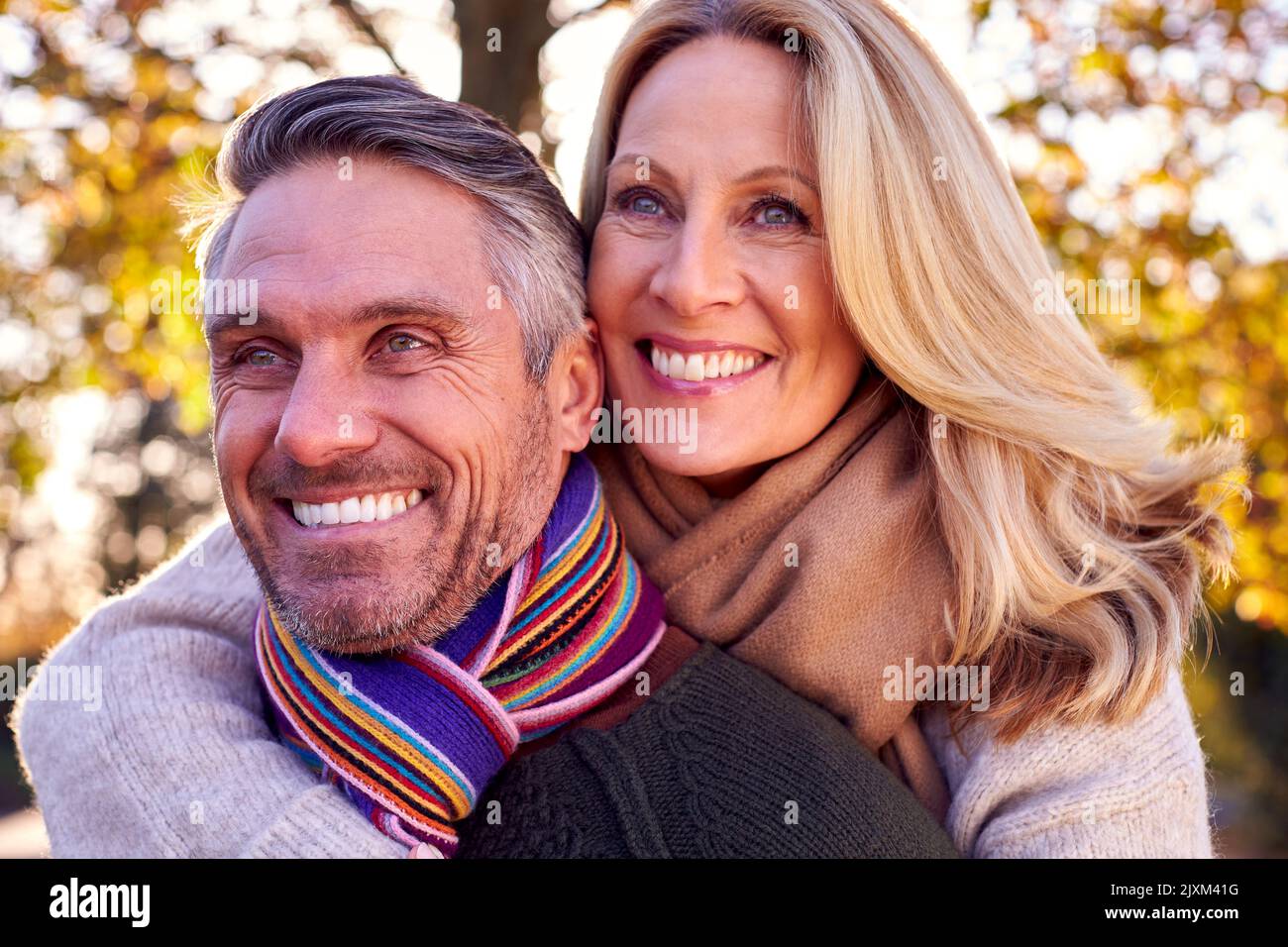 Mujer madura amorosa abrazando al hombre de atrás como pareja jubilada caminar a través de la campiña otoñal Foto de stock