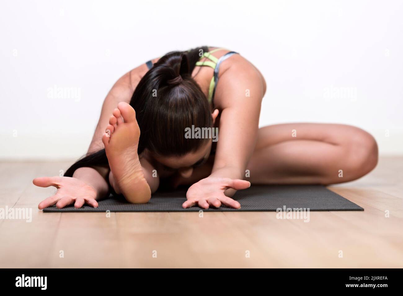 Una mujer soltera, caucásica, de mediados de 30 años de edad en yoga posa contra una pared blanca Foto de stock