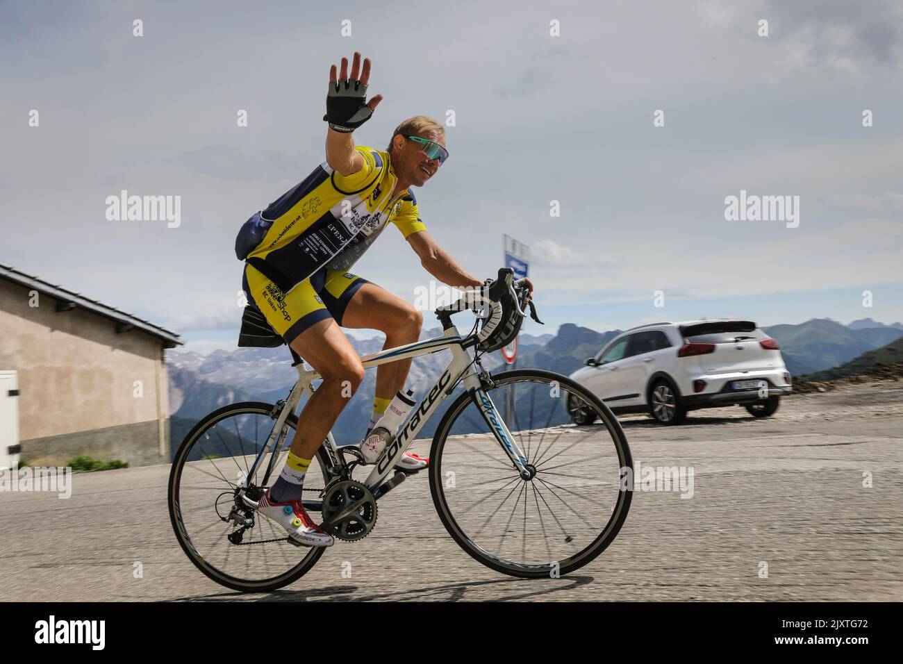 El ciclista sonríe y ondea mientras asciende por un camino de montaña en las Dolomitas, Italia. Foto de stock