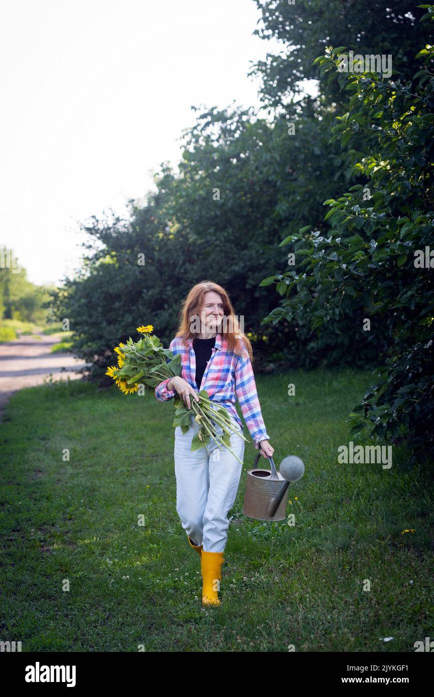 chica sosteniendo un enorme ramo de girasoles en sus manos contra el telón de fondo de un paisaje rural Foto de stock