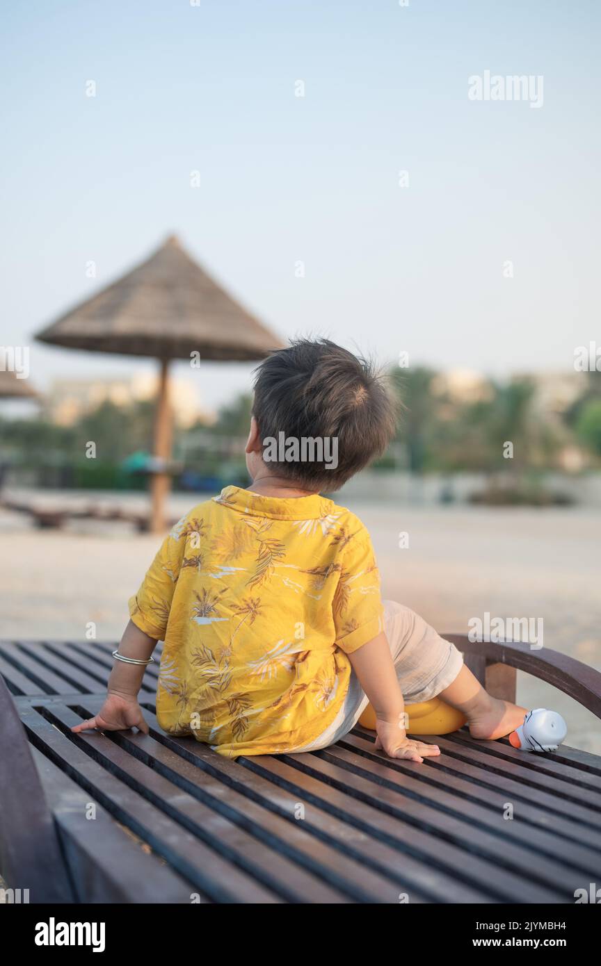 Bebé en una playa de vacaciones sentado en la tumbona al atardecer. Bebé de un año de edad de vacaciones junto al mar sentado en la tumbona Foto de stock