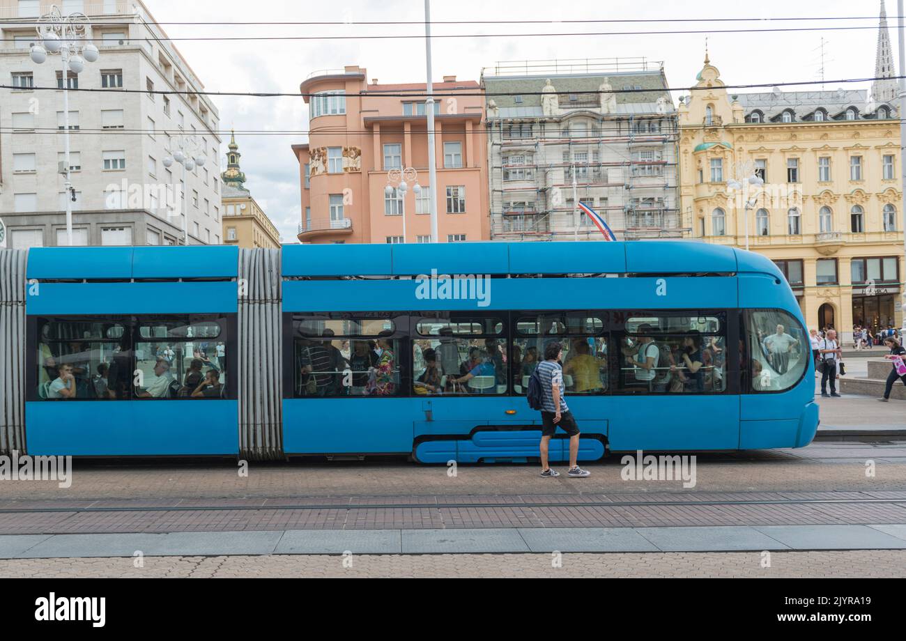 Vista lateral de un tranvía azul articulado con pasajeros en la plaza Ban Jelacic en Zagreb, Croacia, Europa Foto de stock