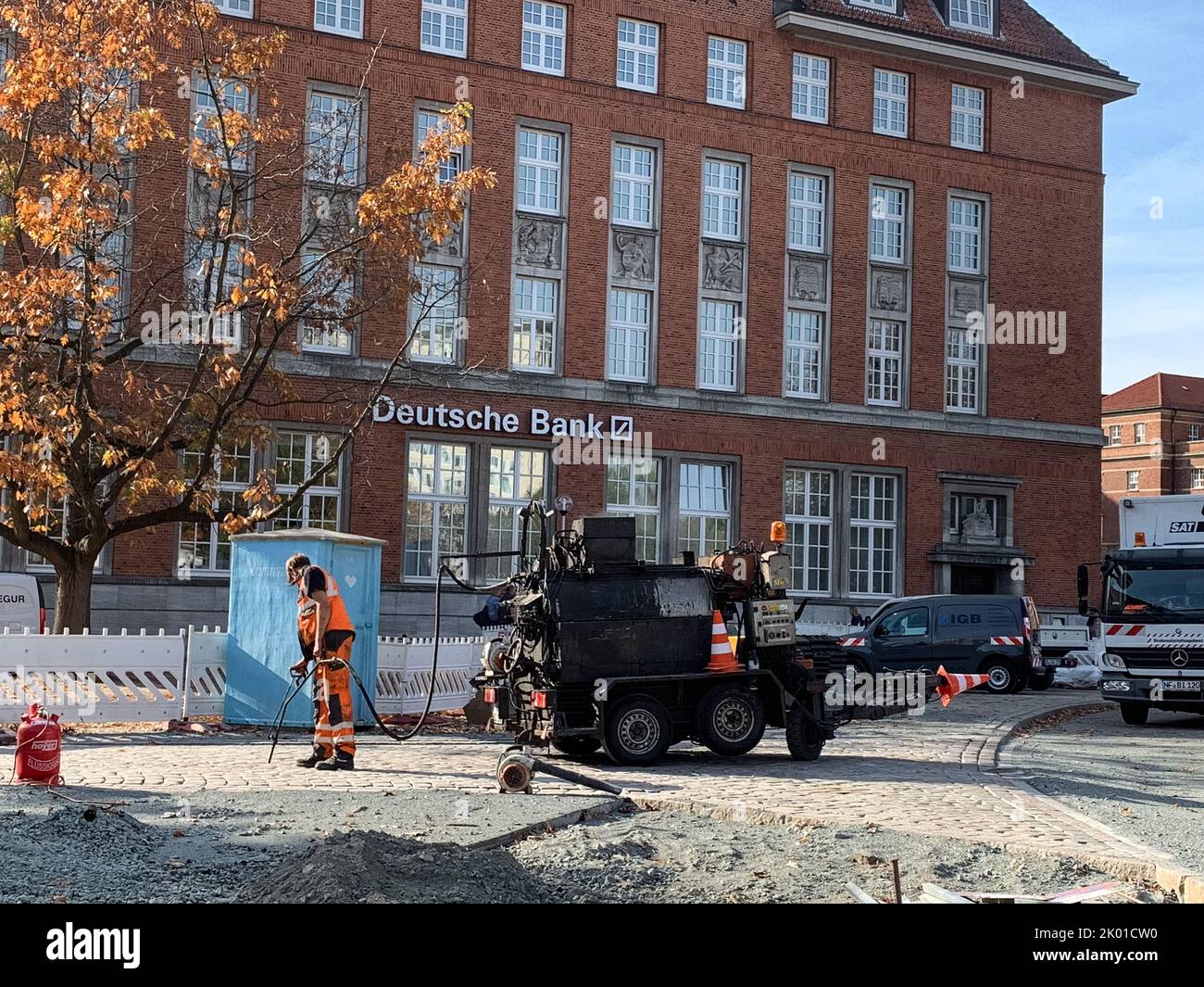 Pflasterarbeiten für Kopfsteipflaster in der Kieler Innenstadt ein Mann verfugt das Straßenpflaster mit Bitumen Foto de stock
