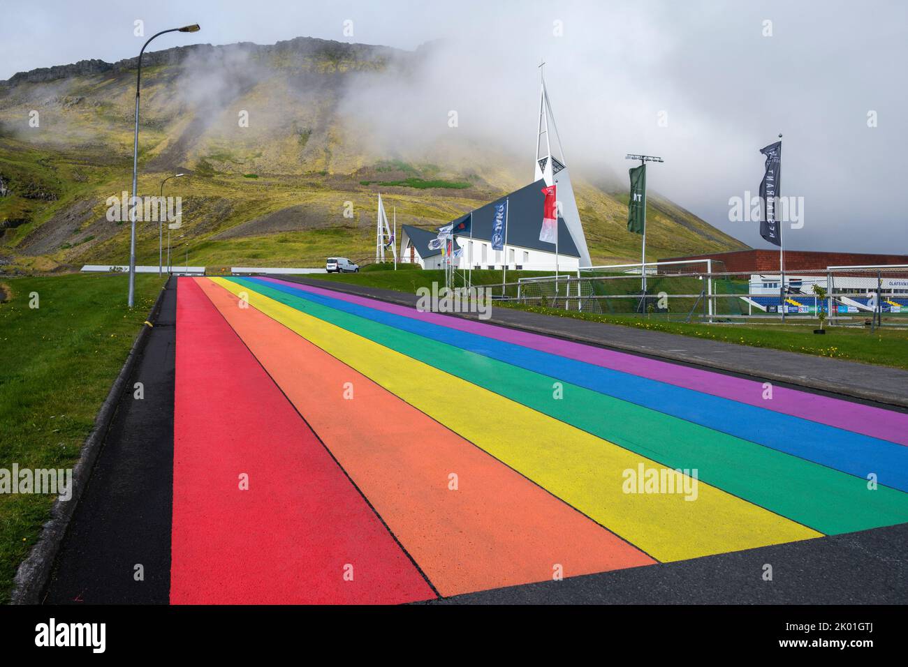 Camino de color arco iris que conduce a la Olafsvikurkirkja (iglesia), Olafsvik, Islandia Foto de stock