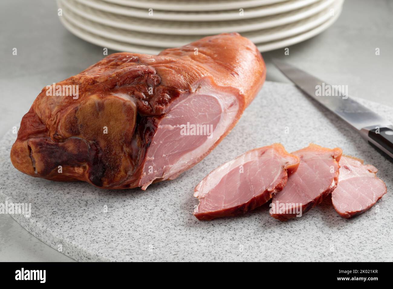 Codillo de cerdo ahumado tradicional croata y rodajas en una tabla de cortar de cerca Foto de stock