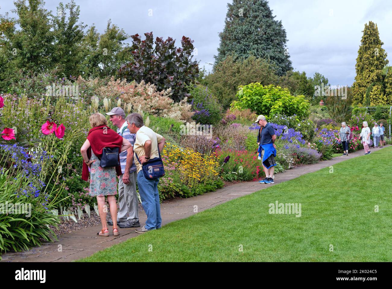 Visitantes en los jardines RHS, Wisley admirando las coloridas fronteras herbáceas en plena floración, Surrey Inglaterra Reino Unido Foto de stock
