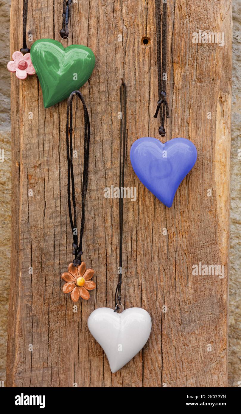 Exhibición de collares colgados en una tabla de madera con racimos en forma de corazón y flor Foto de stock