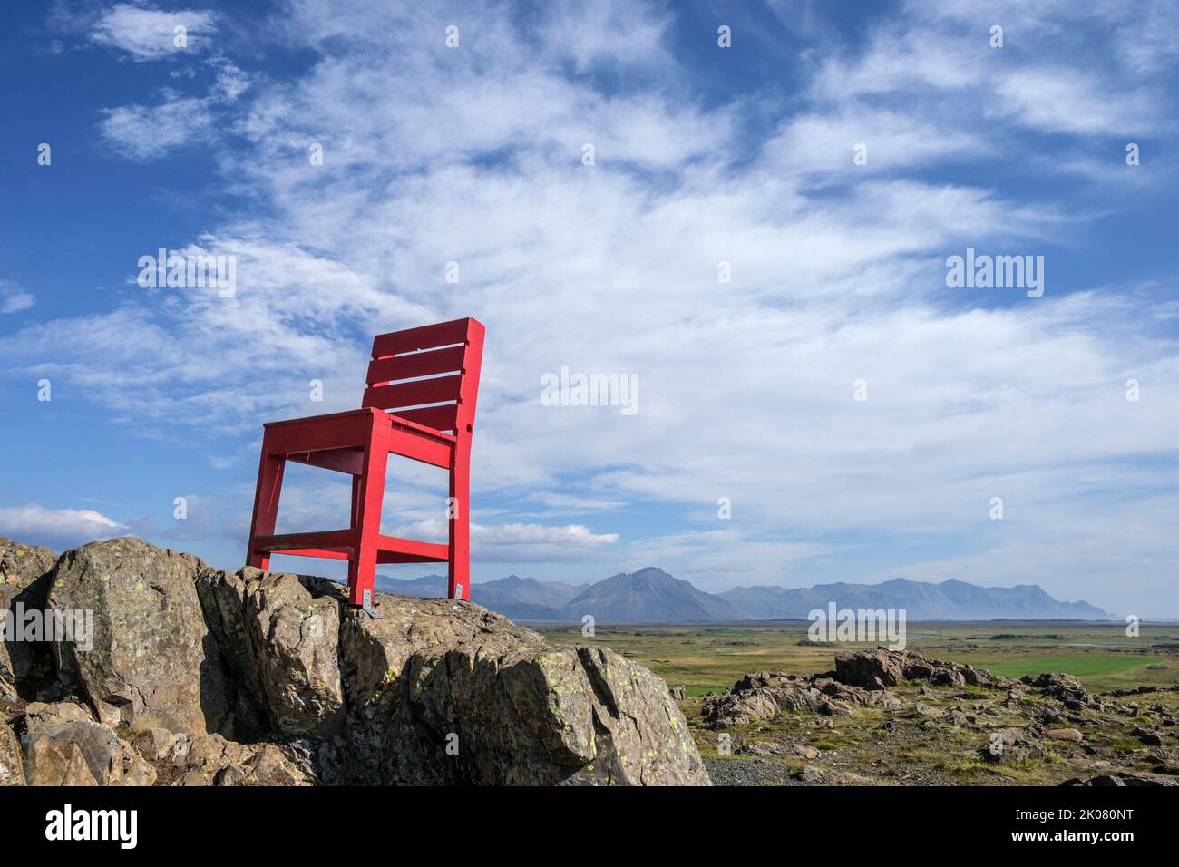 Un lugar popular para los turistas para tomar fotografías en el este de Islandia es esta silla roja, que se ha fijado a un afloramiento rocoso cerca de Hofn Foto de stock
