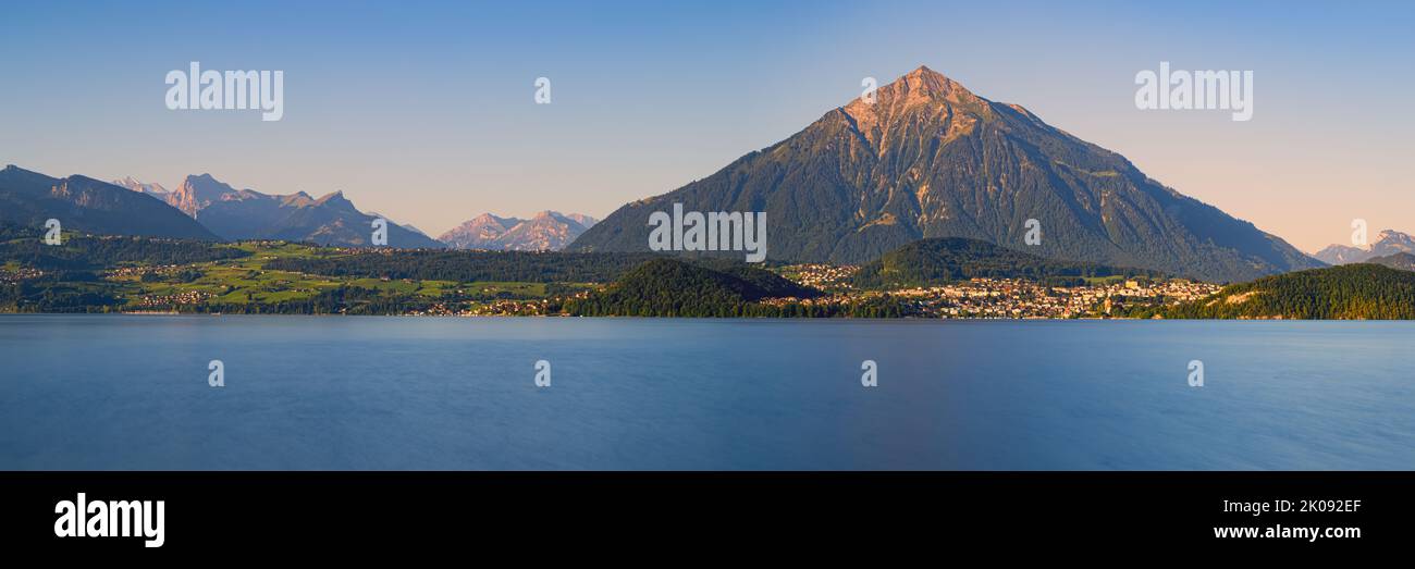 Una amplia imagen panorámica de una hermosa mañana de verano en el lago Thun. La montaña Niesen (2363 metros de altura) se eleva muy por encima del paisaje, pero el plac Foto de stock