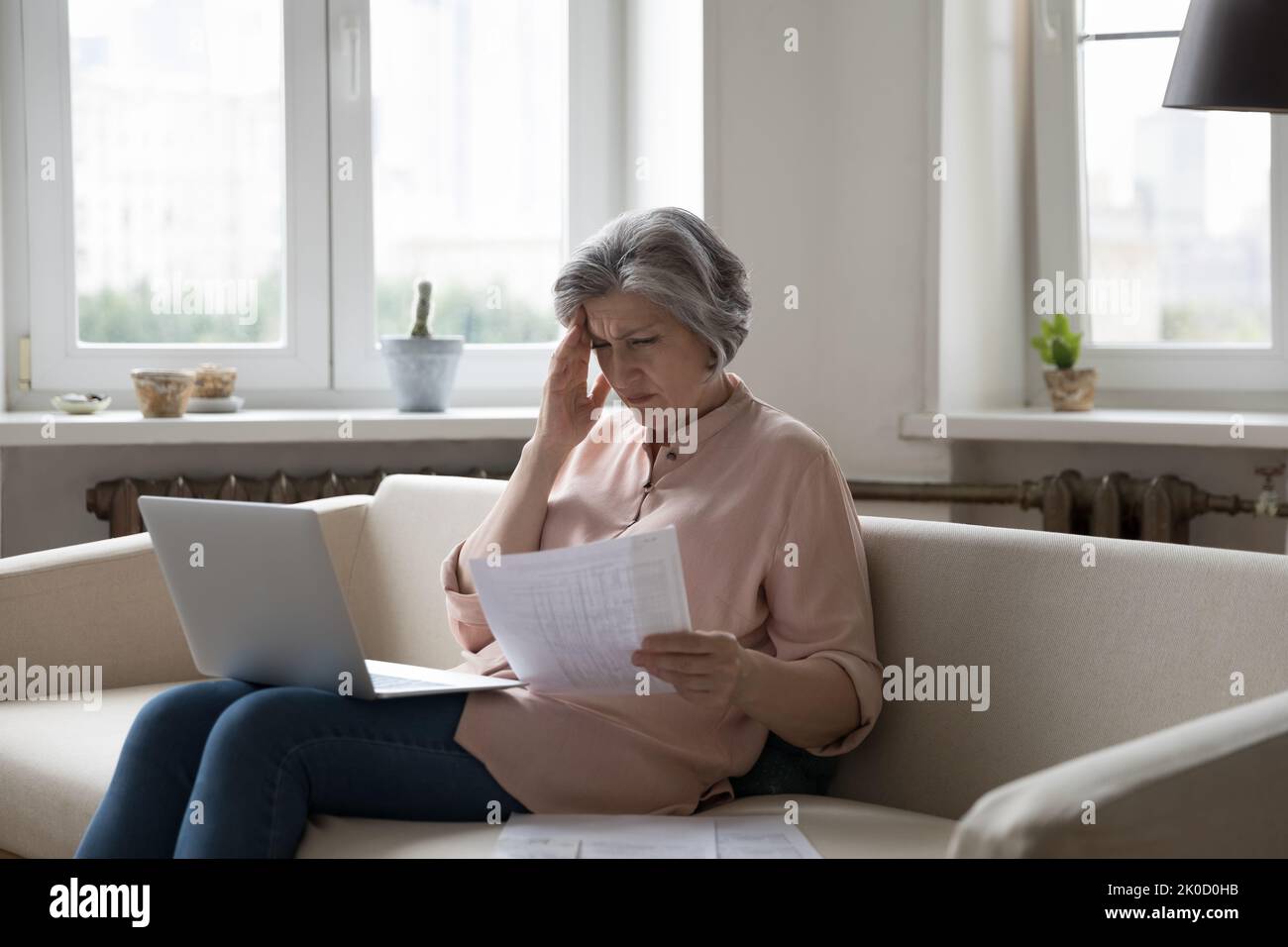 Frustrada molesta a la mujer mayor leyendo factura de papel Foto de stock