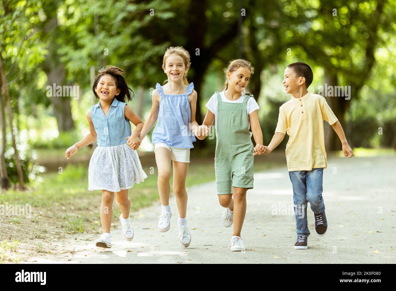 Grupo de lindos niños asiáticos y caucásicos divirtiéndose en el parque Foto de stock