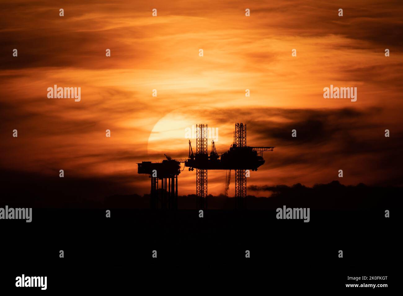 Puesta de sol de plataformas petrolíferas, puesta de sol sobre la plataforma de satélites Lennox en el mar de Irlanda, parte de las plataformas petrolíferas y de gas del complejo Douglas en la bahía de Liverpool, Inglaterra, Reino Unido Foto de stock