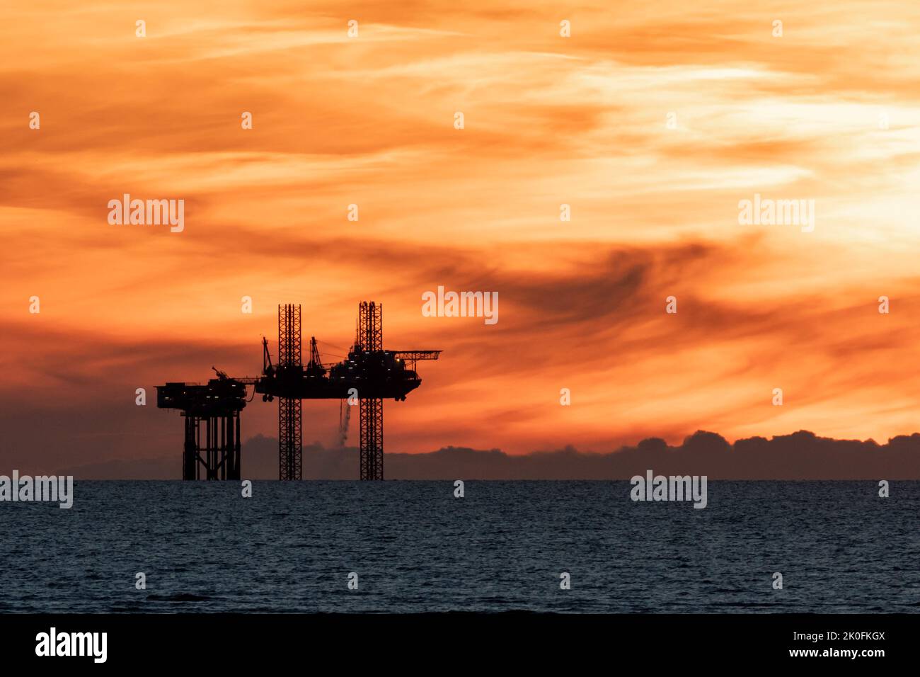 Puesta de sol de plataformas petrolíferas, puesta de sol sobre la plataforma de satélites Lennox en el mar de Irlanda, parte de las plataformas petrolíferas y de gas del complejo Douglas en la bahía de Liverpool, Inglaterra, Reino Unido Foto de stock