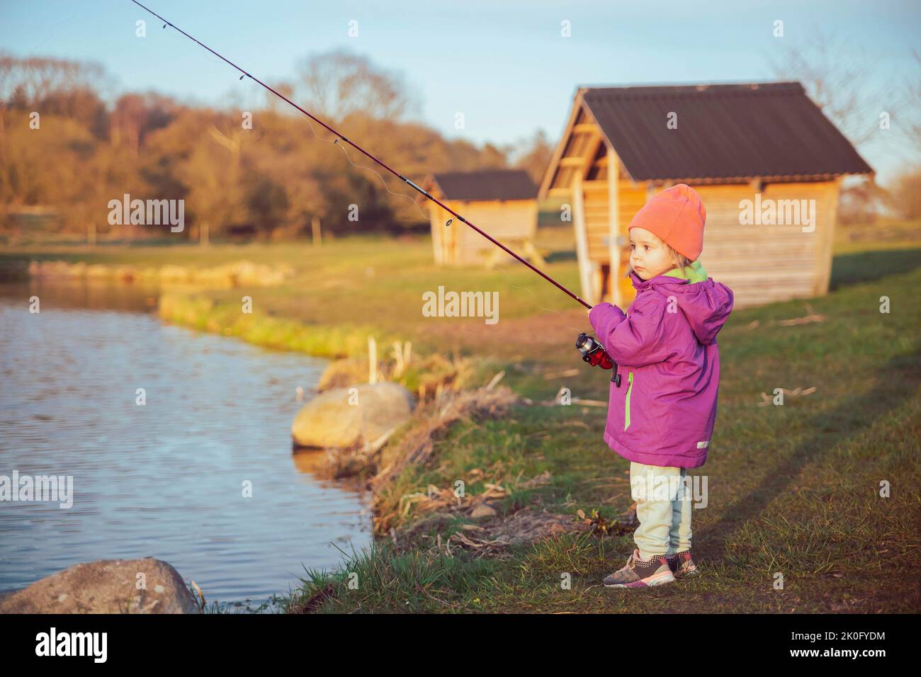 Encantadora pesca infantil en el río al atardecer Foto de stock