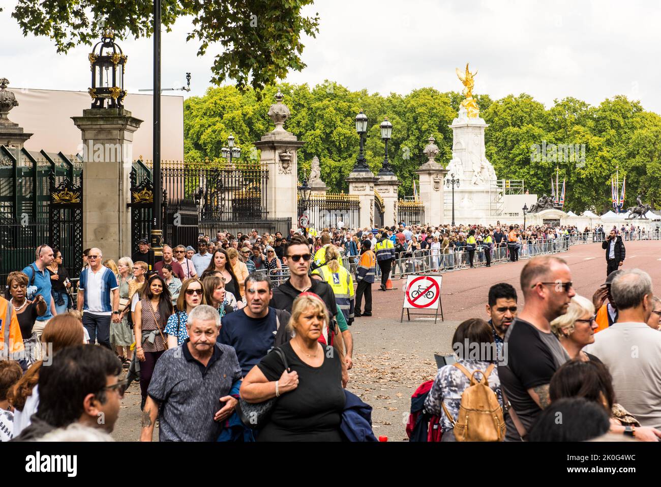 Sombrío público caminando por las puertas del Palacio de Buckingham después de pagar el respeto a la difunta Reina Foto de stock
