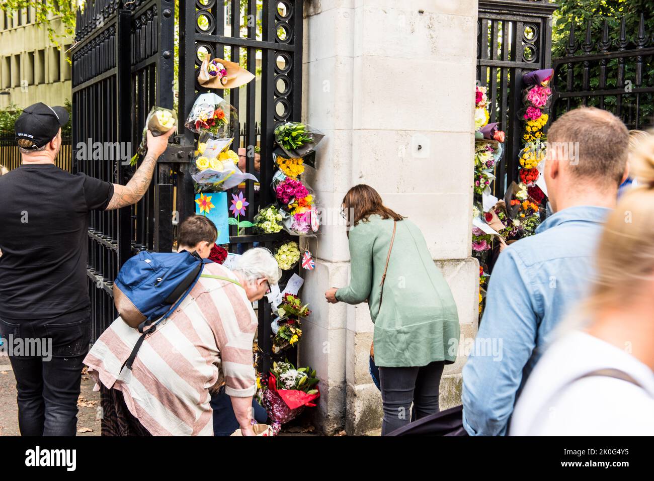 Público dejando ramos florales en las puertas del palacio de Buckingham Foto de stock