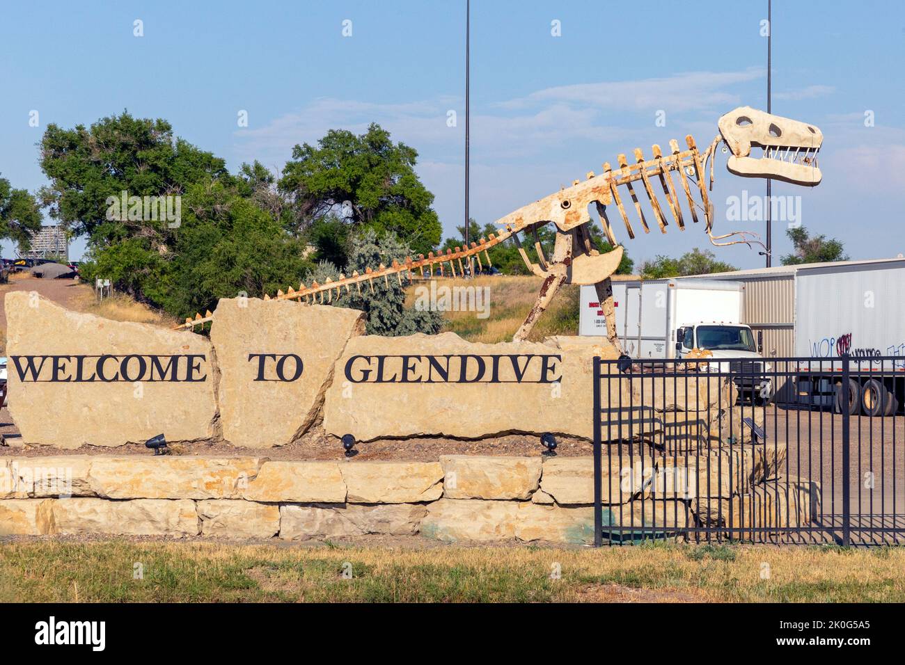 Roadway Bienvenido al cartel de Glendive con la escultura metálica de un dinosaurio en Glendive, Montana. La escultura es un homenaje a los huesos de muchos dinosaurios fo Foto de stock