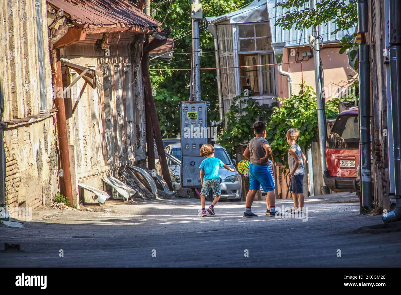 07 16 2019 Tbilisi Georgia - Un grupo de niños juegan a la pelota en un callejón en el casco antiguo de Tbilisi rodeado de edificios desenfrenados Foto de stock