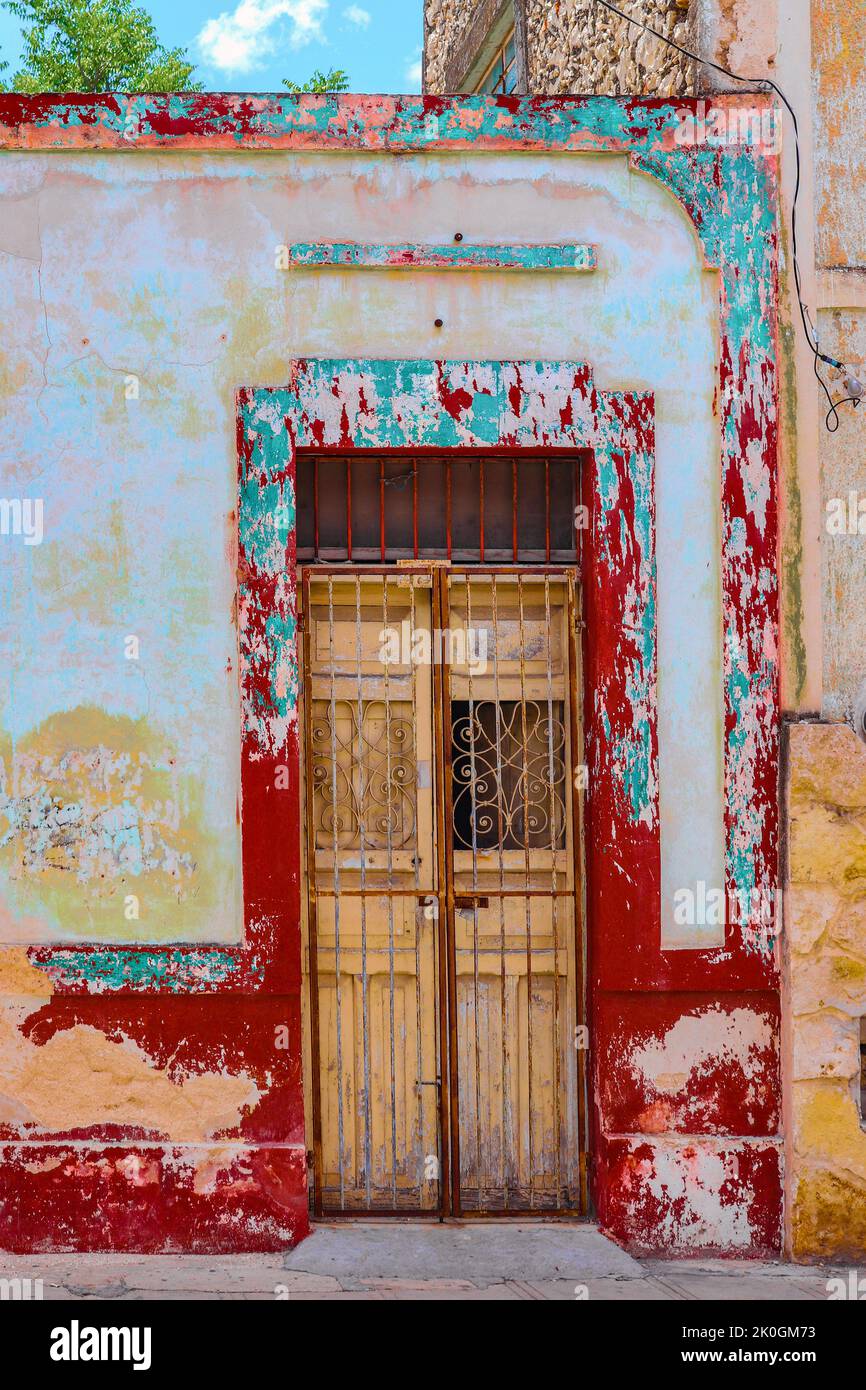 Gruñe colorido alrededor de la puerta rota con acentos de hierro forjado y barras cerradas en frente de la calle en Mérida Yucatán México Foto de stock