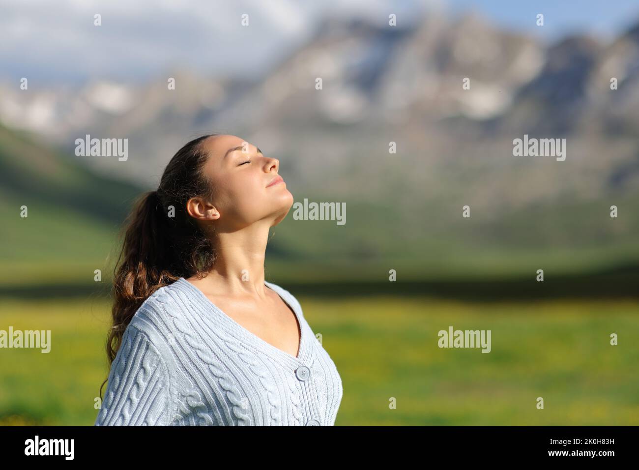 Relajada mujer informal respirando aire fresco en la montaña un día soleado Foto de stock